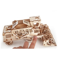 Small wooden model of combine harvester by UGears. Shown assembled with a hand in the picture - a finger touching the model. Doors opening on top of the combine revealing a hidden compartment. 