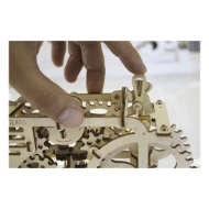 Close-up detail of unpainted, wooden model of a tractor with small, laser cut wooden parts. Made by Ugears. A hand is shown in the picture for a size reference.