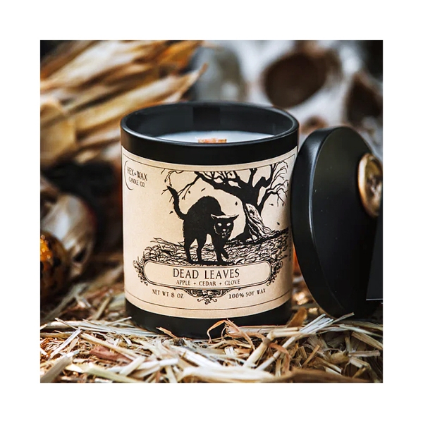 "Dead Leaves" candle with product positioned on hay with dried corn in background, a fall setting.