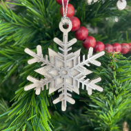 Silver snowflake holiday tree ornament. Carved from natural gourd and painted silver.